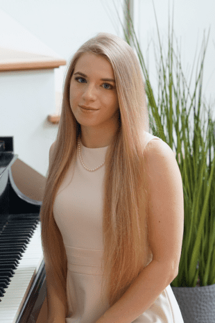 W&20岁的校友Caroline Fedor坐在钢琴凳上微笑着.