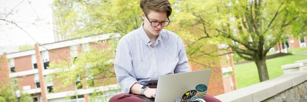 一名学生在笔记本电脑上工作，在罗辛校园中心庭院的墙上学习，在Creosote影响照片拍摄5月1日, 2019年华盛顿 & det365app.